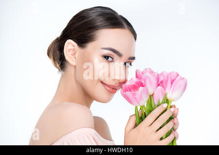 Beautiful woman holding pink tulips near face on white Stock Photo