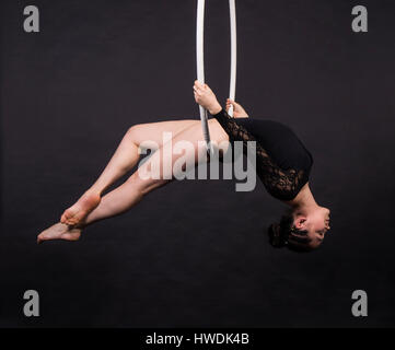 Amazing young gymnast in black leotard stretching the arm near window ...