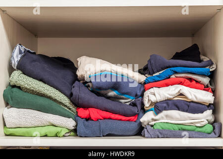A stack of knitted warm woolen clothes in wardrobe close up Stock Photo
