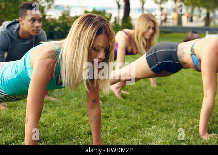 Male and female adults practicing yoga plank pose in park Stock Photo