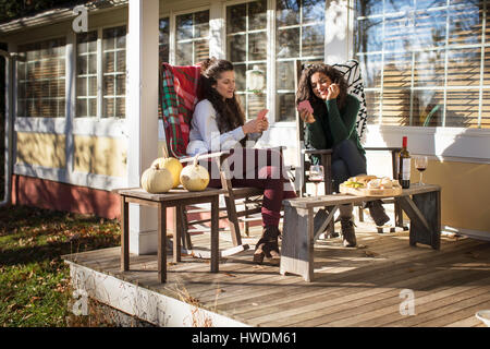 Two young female friends playing card game on patio Stock Photo