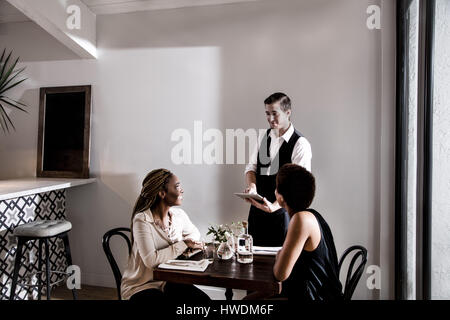 Waiter serving diners in restaurant, waiting using digital tablet Stock Photo