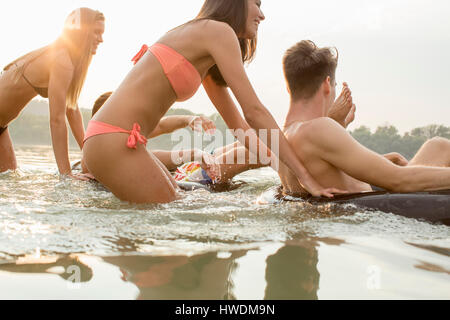 Friends having fun with inflatable ring in river Stock Photo