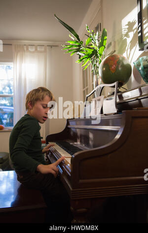 Boy playing piano in living room Stock Photo