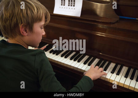 Over shoulder view of boy playing piano in living room Stock Photo