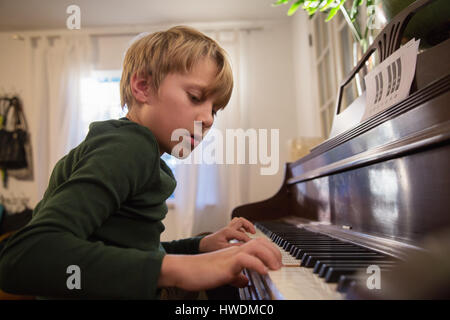 Boy playing piano in living room Stock Photo