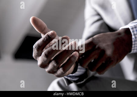 Young man buttoning shirt cuff, close-up Stock Photo