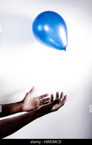Young man catching balloon, close-up Stock Photo
