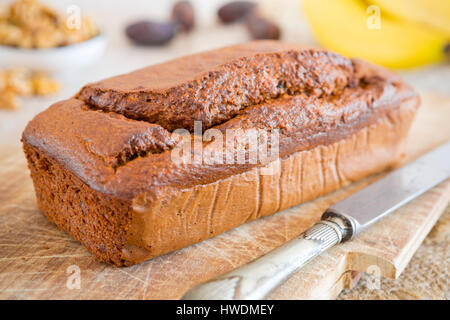 Homemade banana bread with walnuts and dates on a rustic table. Stock Photo