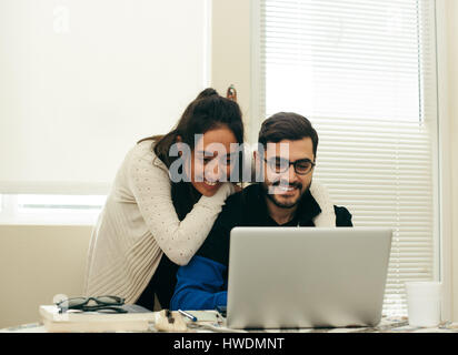 Happy couple using laptop at home Stock Photo