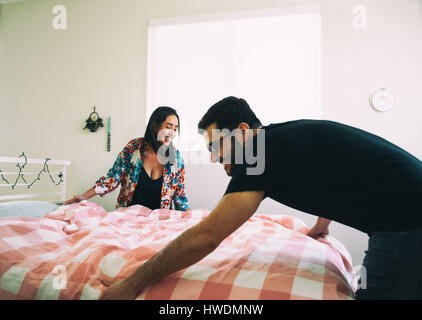 Happy couple making bed together Stock Photo