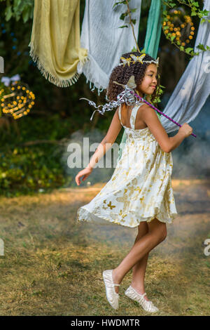 Young girl dressed as fairy, holding wand, playing outdoors Stock Photo