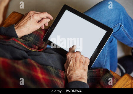 Senior woman sitting in chair, using digital tablet, elevated view Stock Photo