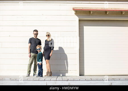 Parents and boy beside wooden building Stock Photo