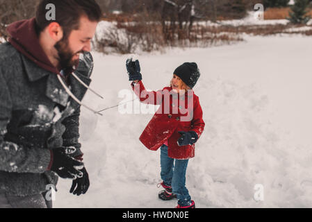 Girl throwing snowball at her father Stock Photo