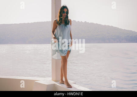 Stylish young woman walking along wall by sea,  Burgaz Island, Istanbul, Turkey Stock Photo