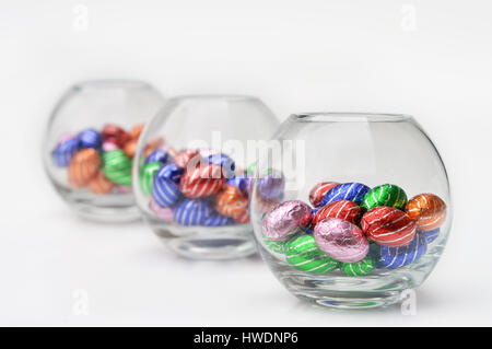 3 Glass spheres filled with chocolate easter-eggs, on white with focus on the first bowl Stock Photo