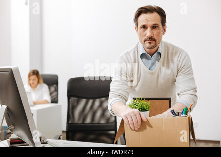 Perplexed manager holding the box and sitting in the office Stock Photo