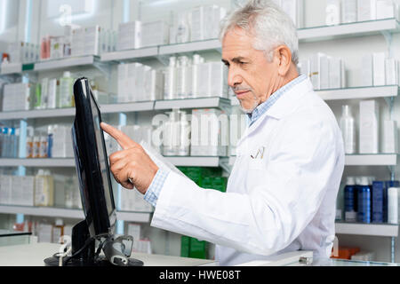 Male Pharmacist Touching Monitor Screen In Pharmacy Stock Photo