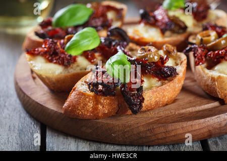 Appetizer bruschetta with sun-dried tomatoes, olives and mozarella. Italian cuisine Stock Photo
