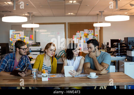 Creative business team discussing over digital tablet at desk in office Stock Photo
