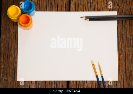 Paint brushes, watercolor paints, color pencils and white paper against white background Stock Photo