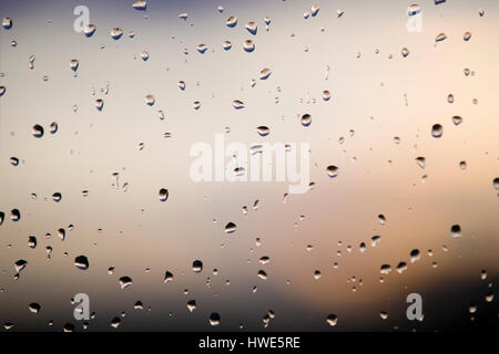 Abstract : Raindrops on a window with the setting sun. Stock Photo