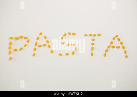 Various pasta arranged in shape of pasta text on white background Stock Photo