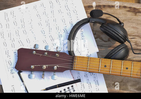 Music book, notepad pen headphone and acoustic guitar on old table Stock Photo