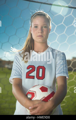 Proud goalie holding soccer ball in goal on sunny day Stock Photo