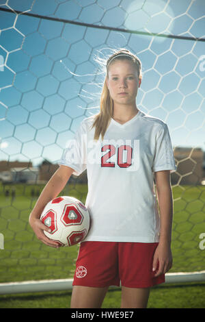 Proud goalie holding soccer ball in goal on sunny day Stock Photo