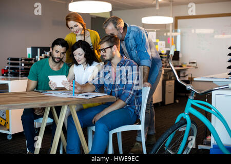 Creative business team discussing over digital tablet in office Stock Photo