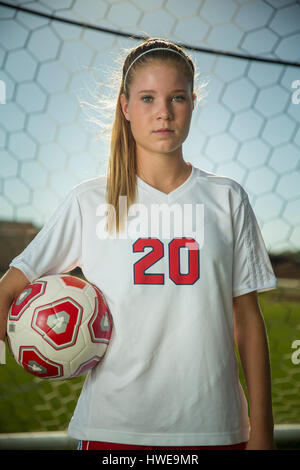 Proud goalie holding soccer ball in goal on sunny day Stock Photo