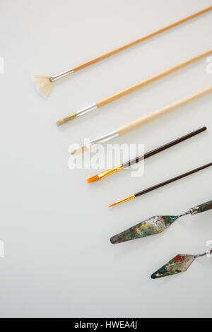 Palette knives and paint brushes arranged in a row on white background Stock Photo