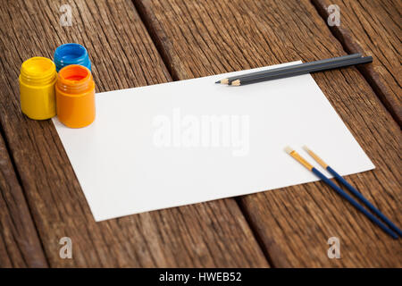 Paint brushes, watercolor paints, color pencils and white paper against white background Stock Photo