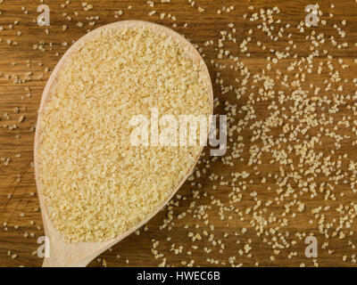 Spoonful of Dried Natural Bulgar Wheat Against a Natural Wood Background Stock Photo
