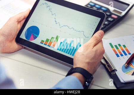 businessman holding digital tablet with graphs and charts report Stock Photo