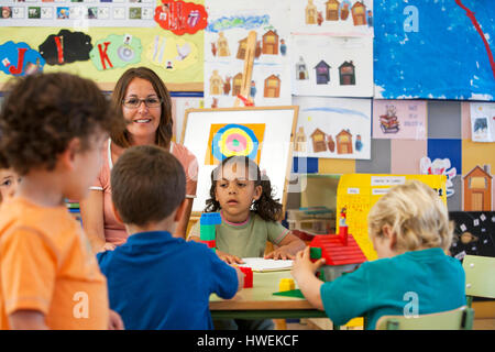 Preschool boys and girls building with toy blocks in classroom Stock Photo