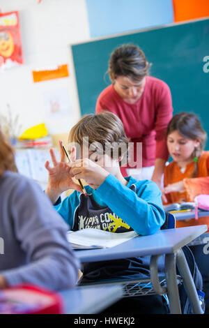 Primary schoolboy counting on fingers in classroom Stock Photo