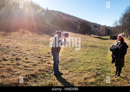 Man taking photograph of woman and baby boy, using medium format camera, in rural setting, Italy Stock Photo