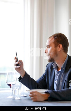 Man sitting at dinner table, using smartphone Stock Photo