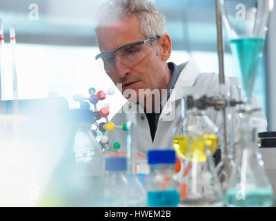 Researcher using a molecular model to understand a chemical formula in a laboratory Stock Photo