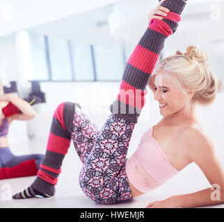 Young female ballet dancer sitting on floor stretching leg Stock Photo