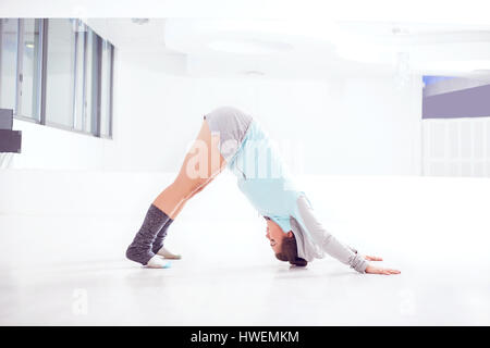 Portrait of young female ballet dancer practicing in dance studio, bending forward Stock Photo