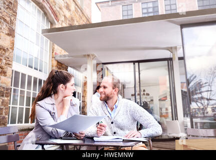 Businesswoman and man discussing paperwork on office patio Stock Photo