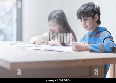 Boy and sister doing homework at kitchen table Stock Photo