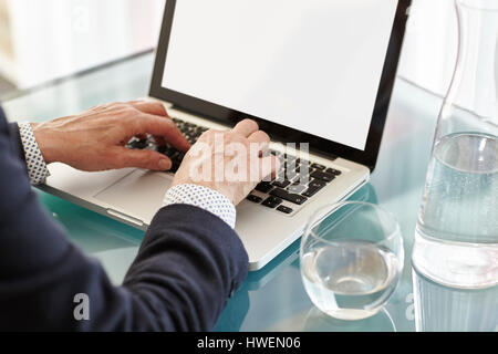 Hands of senior woman typing on laptop at desk Stock Photo