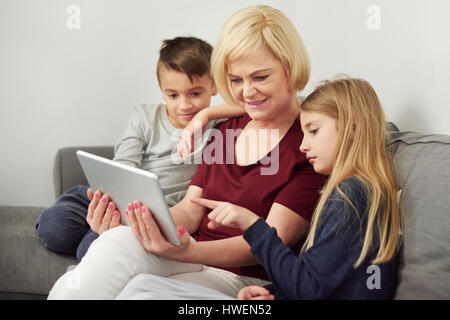 Grandmother and grandchildren using digital tablet on sofa Stock Photo
