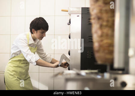Young woman cooking food in fast food shop Stock Photo