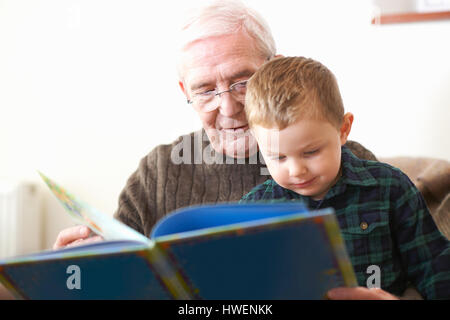 Senior man reading book to grandson Stock Photo